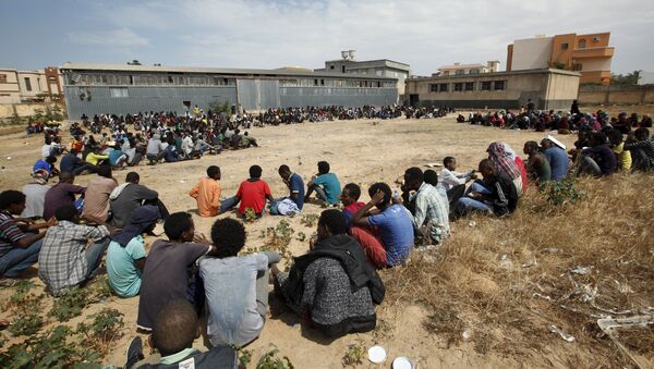 Migrants sit at temporary detention centre after they were detained by Libyan authorities in Tripoli, Libya June 9, 2015 - Sputnik Mundo