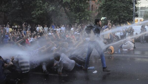 Protesters are hit by jets of water released from a riot police vehicle during a rally against a recent decision to to increase the tariff on electricity, in Yerevan, Armenia, June 23, 2015 - Sputnik Mundo
