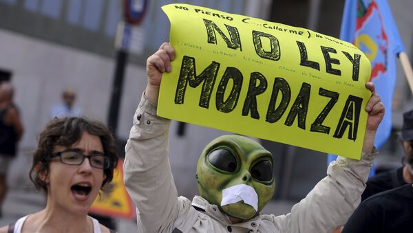 A man wearing a mask with a tape over the mouth holds up a sign during a protest against the Spanish government's new security law in Gijon, northern Spain, June 30, 2015. - Sputnik Mundo