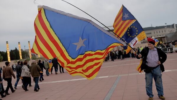 A pro-independence Catalans holds a large Catalan flag as others arrive to an event organised by the Catalan independence movement at the Palau Sant Jordi - Sputnik Mundo
