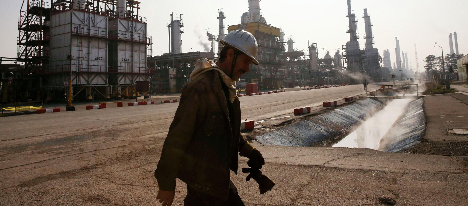 Trabajador petrolero iraní camina cerca una refinería de petróleo en Teherán, Irán - Sputnik Mundo, 1920, 22.01.2021