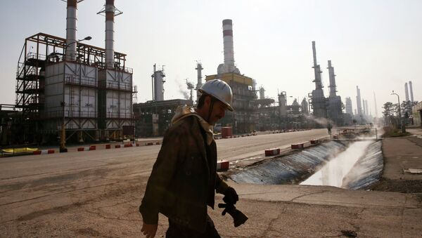 Trabajador petrolero iraní camina cerca una refinería de petróleo - Sputnik Mundo