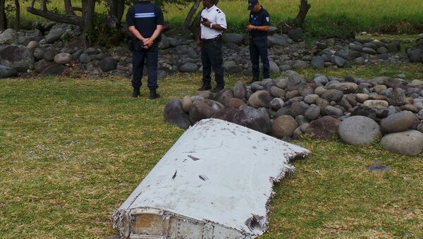 French gendarmes and police stand near a large piece of plane debris which was found on the beach in Saint-Andre, on the French Indian Ocean island of La Reunion, July 29, 2015. - Sputnik Mundo