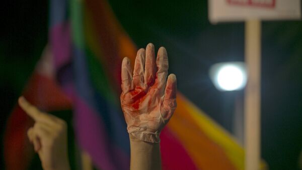 Manifestante levanta el mano en un guante cubierto de sangre falsa durante protestas contra violencia contra comunidad gay en Israel - Sputnik Mundo