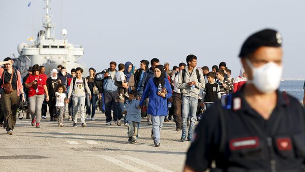 Refugiados sirios acompañados por carabineros italianos después de desembarcar en Augusta, Italia - Sputnik Mundo