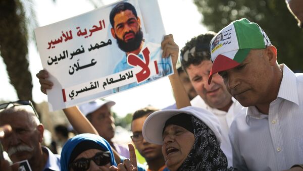 Familiares protestan contra alimentación a la fuerza de prisionero palestino Mohammed Allan, visto en el póster - Sputnik Mundo