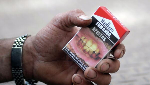 Cajetilla de cigarrillos con una advertencia 'Fumando, apestas' - Sputnik Mundo