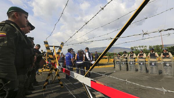 Colombian policemen stand guard in front of the border with Venezuelan policemen - Sputnik Mundo