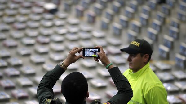 Policíaco toma fotos de paquetes de cocaína presentados por la Policía para la prensa en Bogota, Colombia - Sputnik Mundo