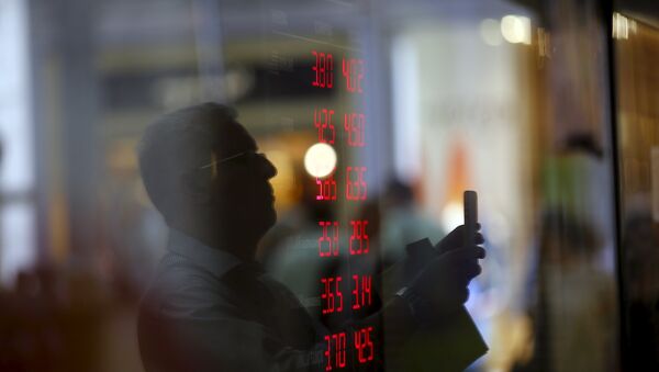 Reflejo de un hombre en el vidrio mientras toma imágenes de un tablero que muestra tipos de cambio de dólares y otras divisas - Sputnik Mundo