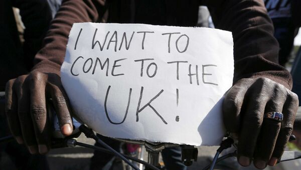 Migrante con un póster que dice Quiero llegar al Reino Unido! - Sputnik Mundo