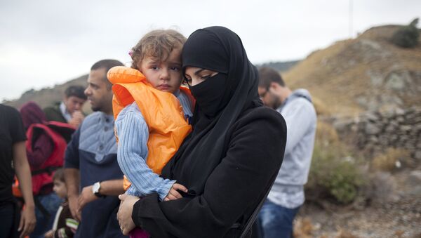 A Syrian refugee holds a child following their arrival on the Greek island of Lesbos after crossing a part of the Aegean Sea from the Turkish coast, September 29, 2015. - Sputnik Mundo
