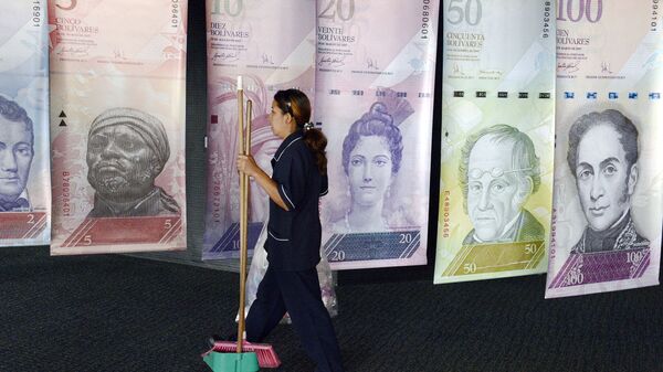 A woman walks past banners portraying the Venezuelan currency, the Bolivar, at the Venezuelan Central Bank in Caracas - Sputnik Mundo