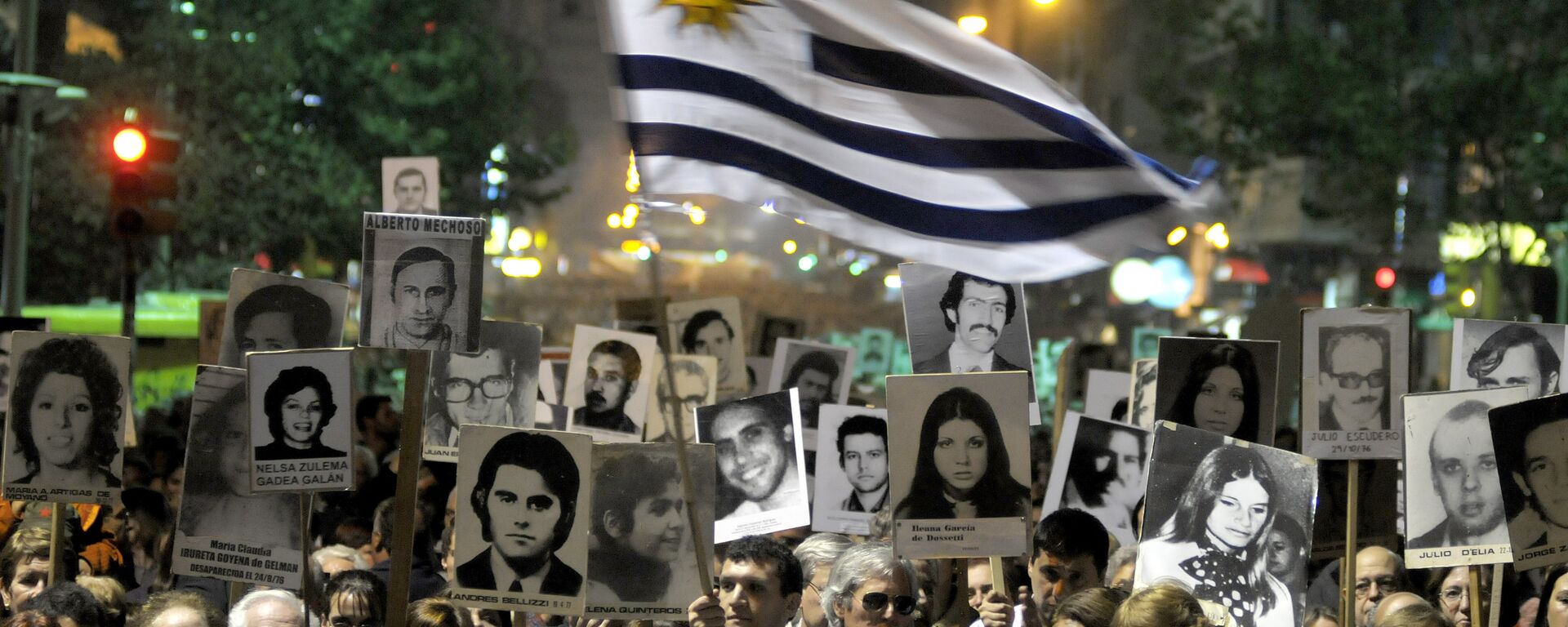 Demonstrators, one waving an Uruguayan flag, carry signs with images of people missing during Uruguay's 1973-85 dictatorship during a march in Montevideo, Uruguay - Sputnik Mundo, 1920, 16.01.2023