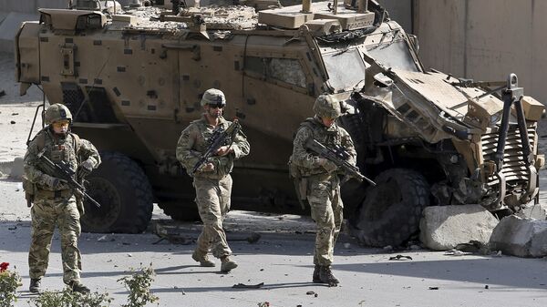 NATO soldiers walk in front of a damaged NATO military vehicle at the site of a suicide car bomb blast in Kabul, Afghanistan, October 11, 2015. - Sputnik Mundo