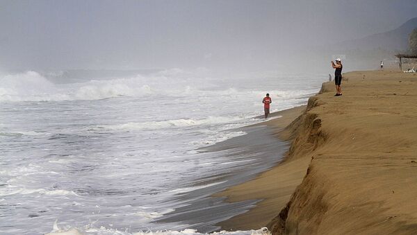 Un hombre toma fotografías de las olas en la playa de Acapulco, México (archivo) - Sputnik Mundo