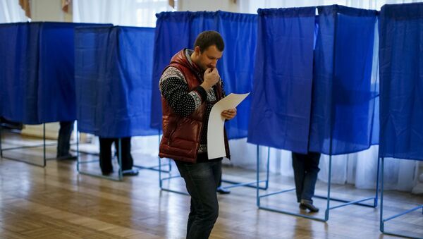 A man reads his ballot during a regional election at a polling station in Kiev, Ukraine - Sputnik Mundo