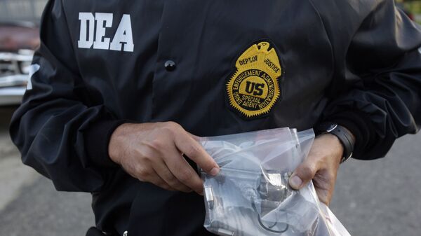A DEA agent shows a gun allegedly seized from a suspected drug dealer after his arrest during a raid on a public housing project in Mayaguez, Puerto Rico, Friday, July 9, 2010. - Sputnik Mundo