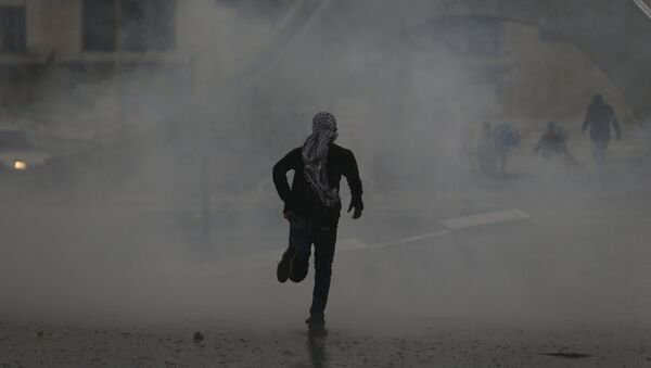 Manifestante palestino corre durante enfrentamientos con las tropas israelíes - Sputnik Mundo