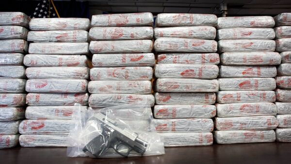 A firearm and 154 pounds of heroin worth at least $50 million are displayed at a Drug Enforcement Administration news conference. - Sputnik Mundo
