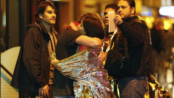 Hombre abraza a una mujer cerca de la sala de Bataclan antes de ser evacuados por autobús - Sputnik Mundo