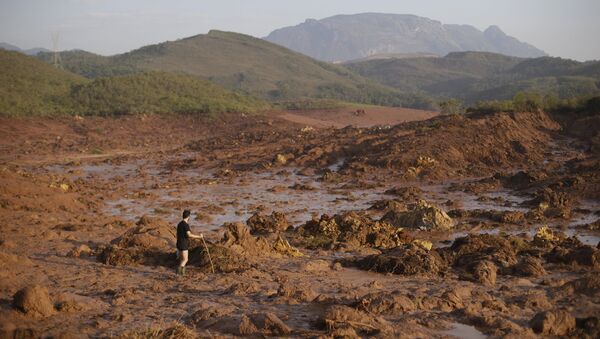A man walks following a mudslide after a dam owned by Vale SA and BHP Billiton Ltd burst in Mariana, Brazil - Sputnik Mundo