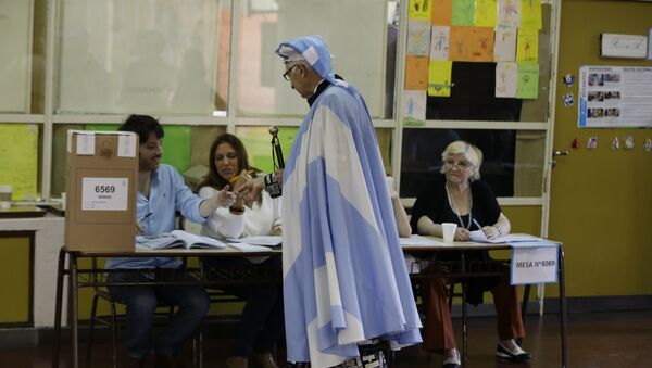 Un votante envuelto en una bandera argentina presenta su identificación en un puesto de votación durante la segunda vuelta de las elecciones presidenciales en Buenos Aires, Argentina, noviembre de 2015 - Sputnik Mundo
