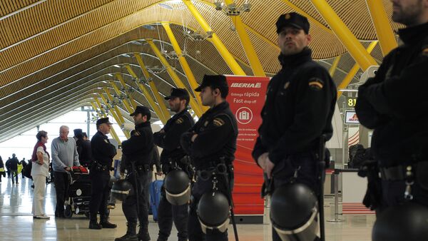 Police officers stand guard as passengers walk to a check-in counter during a protest by Iberia employees at Barajas international airport in Madrid, Spain, Monday, March 4, 2013. - Sputnik Mundo