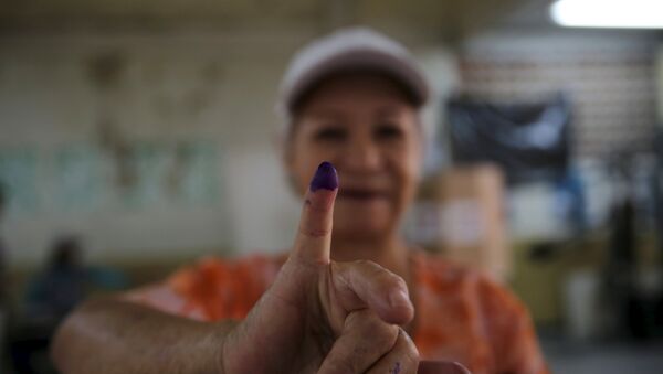 A women shows her ink-stained finger after casting her vote during a legislative election, in Caracas December 6, 2015 - Sputnik Mundo