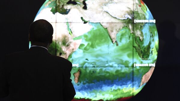 A conference attendee looks at a projection of the Earth on the opening day of the COP 21 United Nations conference on climate change, on November 30, 2015 in Le Bourget - Sputnik Mundo