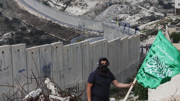 Palestino con la bandera de Hamás frente al muro israelí (archivo) - Sputnik Mundo