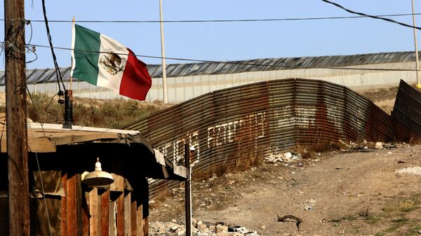 Una bandera mexicana ondea cerca del muro que separa México de los EEUU en Tijuana - Sputnik Mundo