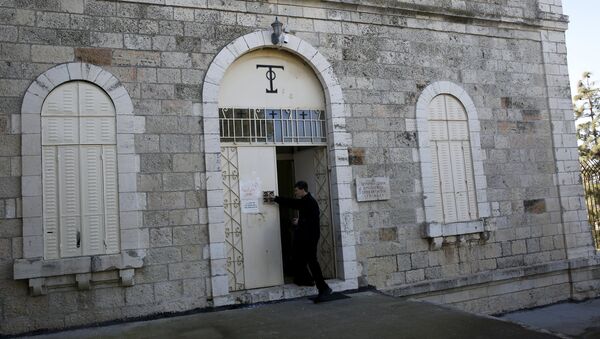Un monje trata de limpiar las pintadas de la puerta de la Abadía de la Dormición de Jerusalén - Sputnik Mundo