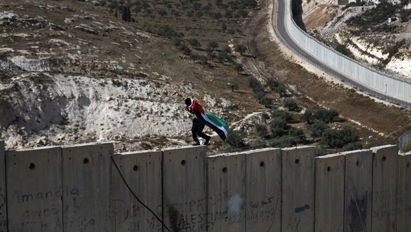 Un palestino camina sobre el muro de Cisjordania, construido por Israel (archivo) - Sputnik Mundo
