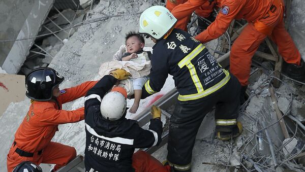 Equipo de rescate ayuda a un niño tras el sismo en Taiwán - Sputnik Mundo