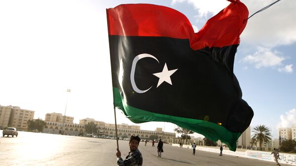 A Libyan man waves his national flag as protesters gather for a demonstration calling on the international community to lift the ban on arming or munitioning the Libyan army, in the eastern coastal city of Benghazi on February 27, 2015. - Sputnik Mundo