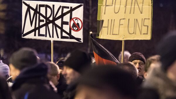 Protestas en Erfurt, Alemania. El cartel de la izquierda pone el nombre tachado de la canciller alemana Ángela Merkel: Merkel. El cartel de la derecha dice: Putin,  ayúdanos - Sputnik Mundo