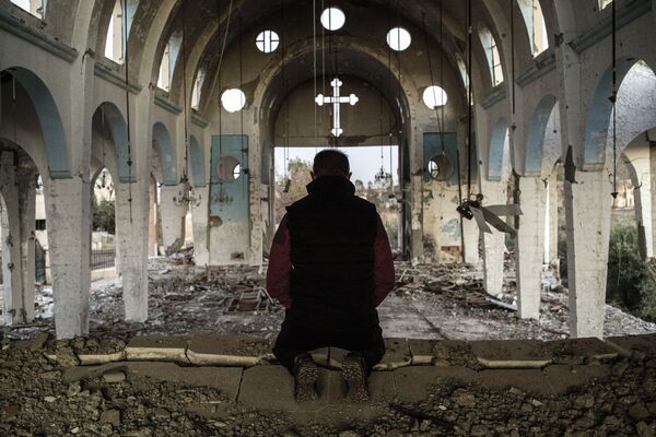 Un cristiano reza en la iglesia destruida en Siria - Sputnik Mundo