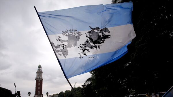 Un hombre sostiene una bandera argentina con la imagen de las Islas Malvinas. - Sputnik Mundo