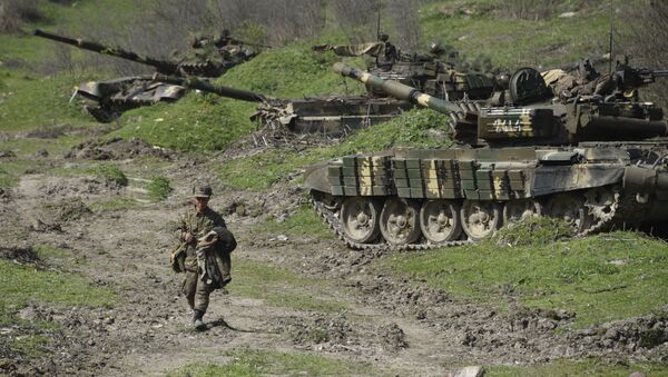 A soldier of the defense army of Nagorny Karabakh walks past tanks at a field position outside the village of Mataghis, some 70km north of Karabakh's capital Stepanakert, on April 6, 2016 - Sputnik Mundo