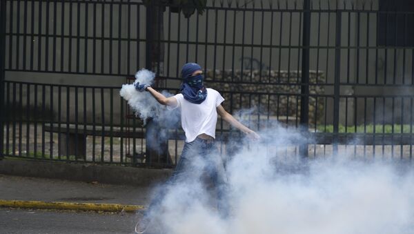 A man protesting against new emergency powers decreed this week by President Nicolas Maduro clashes with policemen in Caracas on May 18, 2016. - Sputnik Mundo