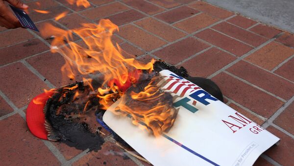 Los manifestantes anti-Trump queman objetos de la campaña del candidato presidencial republicano en San Diego, California - Sputnik Mundo