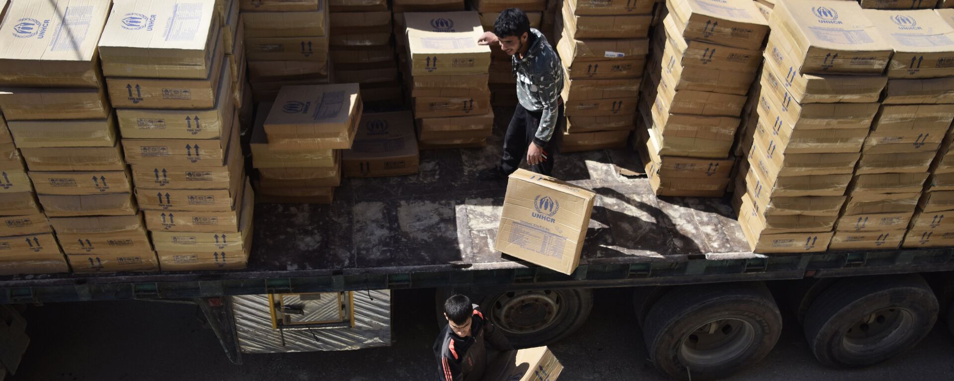Hombres sirios descargan paquetes de ayuda proporcionados por el Programa Mundial de Alimentos (PMA) de la ONU y la Media Luna Roja Árabe Siria - Sputnik Mundo, 1920, 09.01.2023