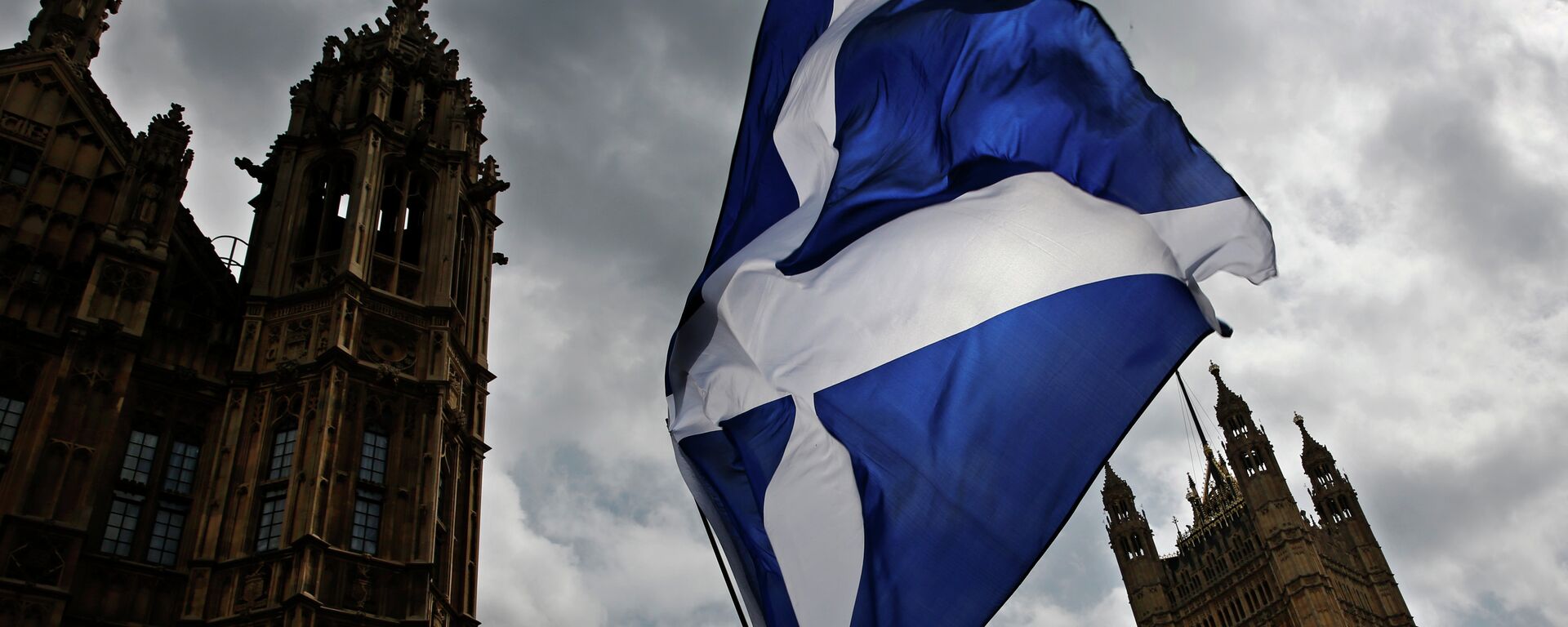 A member of public flies a giant Scottish Saltire flag outside the Houses of Parliament shortly before Scotland First Minister Nicola Sturgeon posed with newly-elected Scottish National Party (SNP) MPs during a photocall in London on May 11, 2015 - Sputnik Mundo, 1920, 30.03.2021