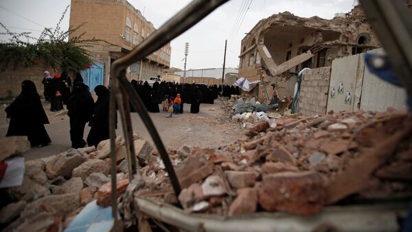 Women walk past destroyed houses during a vigil marking one year since a Saudi-led air strike on a residential area in Sanaa, Yemen June 21, 2016. - Sputnik Mundo