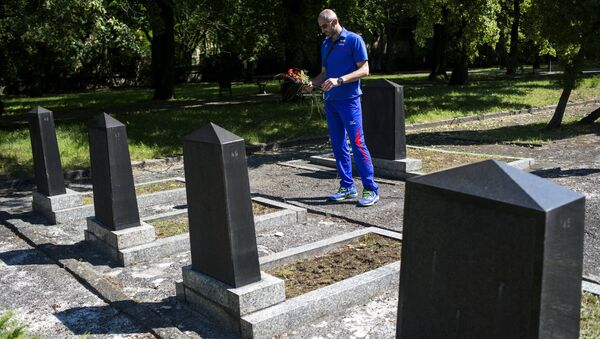 El hombre deposita flores en una tumba - Sputnik Mundo