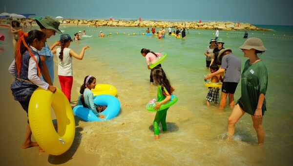 Voluntarios de la ONG Min el Bahar ayudan a niños palestinos a meterse en el agua, en la playa de Tel Baruch, en Tel Aviv - Sputnik Mundo