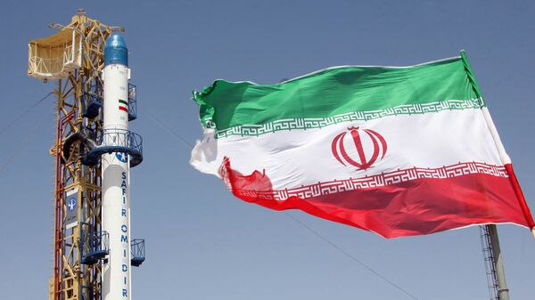 Iranian flag fluttering in front of Iran's Safir Omid rocket, which is capable of carrying a satellite into orbit, before it's launch in a space station at an undisclosed location in the Islamic republic - Sputnik Mundo
