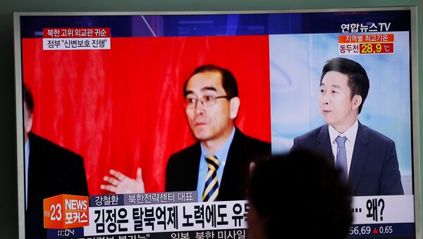 A passengers walks past a TV broadcasting a news report on Thae Yong Ho, North Korea's deputy ambassador in London, who has defected with his family to South Korea, at a railway station in Seoul - Sputnik Mundo