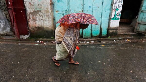 A woman walks on a street during rains in Kolkata - Sputnik Mundo